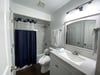 The Nautical Nights second bathroom has a beautiful white vanity and modern lighting, and a tiled tub/shower combo