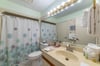 The guest bathroom is located off the hallway and features a single vanity and tub/shower combo